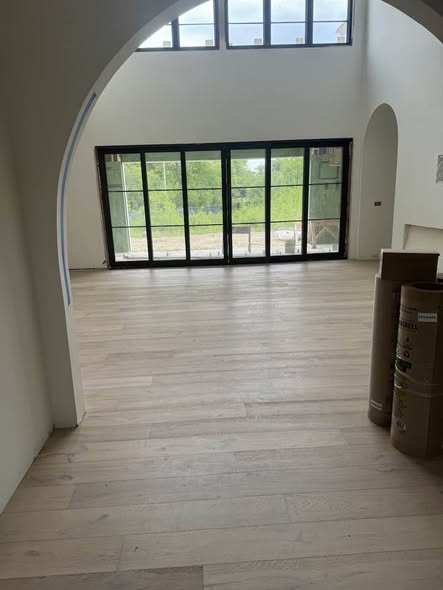 Light hardwood flooring installed continuously through curved archways in an MGM Floors project