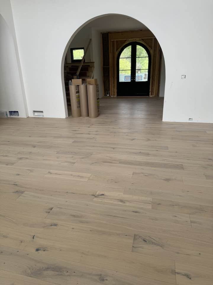 Light hardwood flooring extending through curved openings in an MGM project