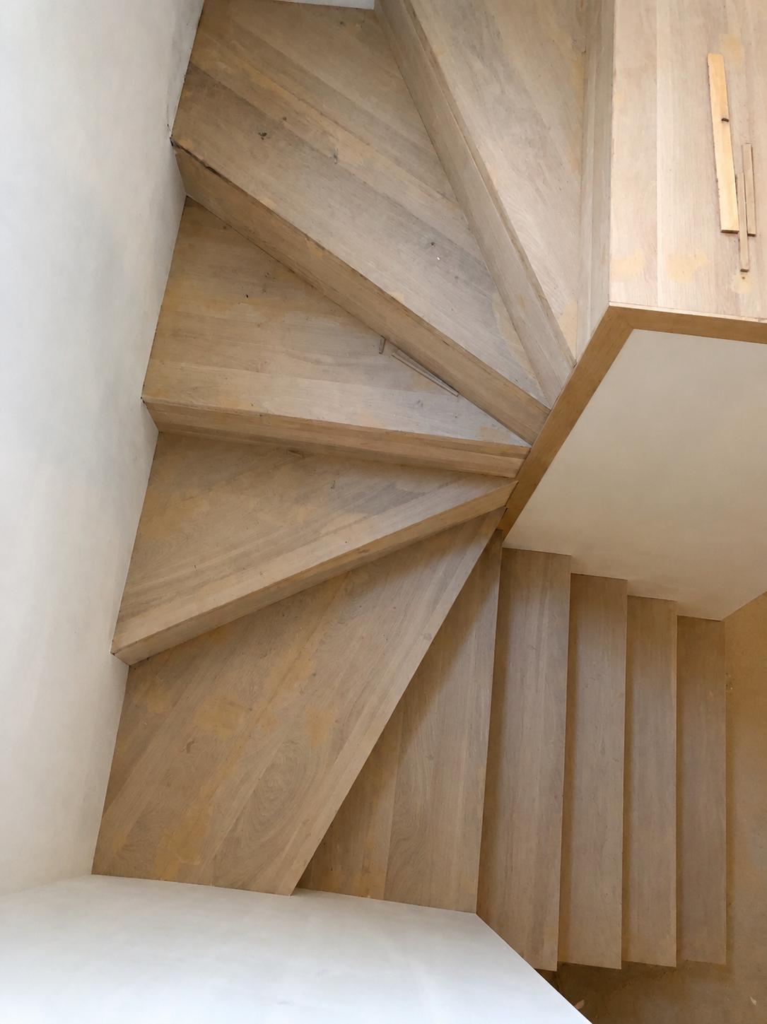 Staircase before refinishing, with unfinished light wood treads